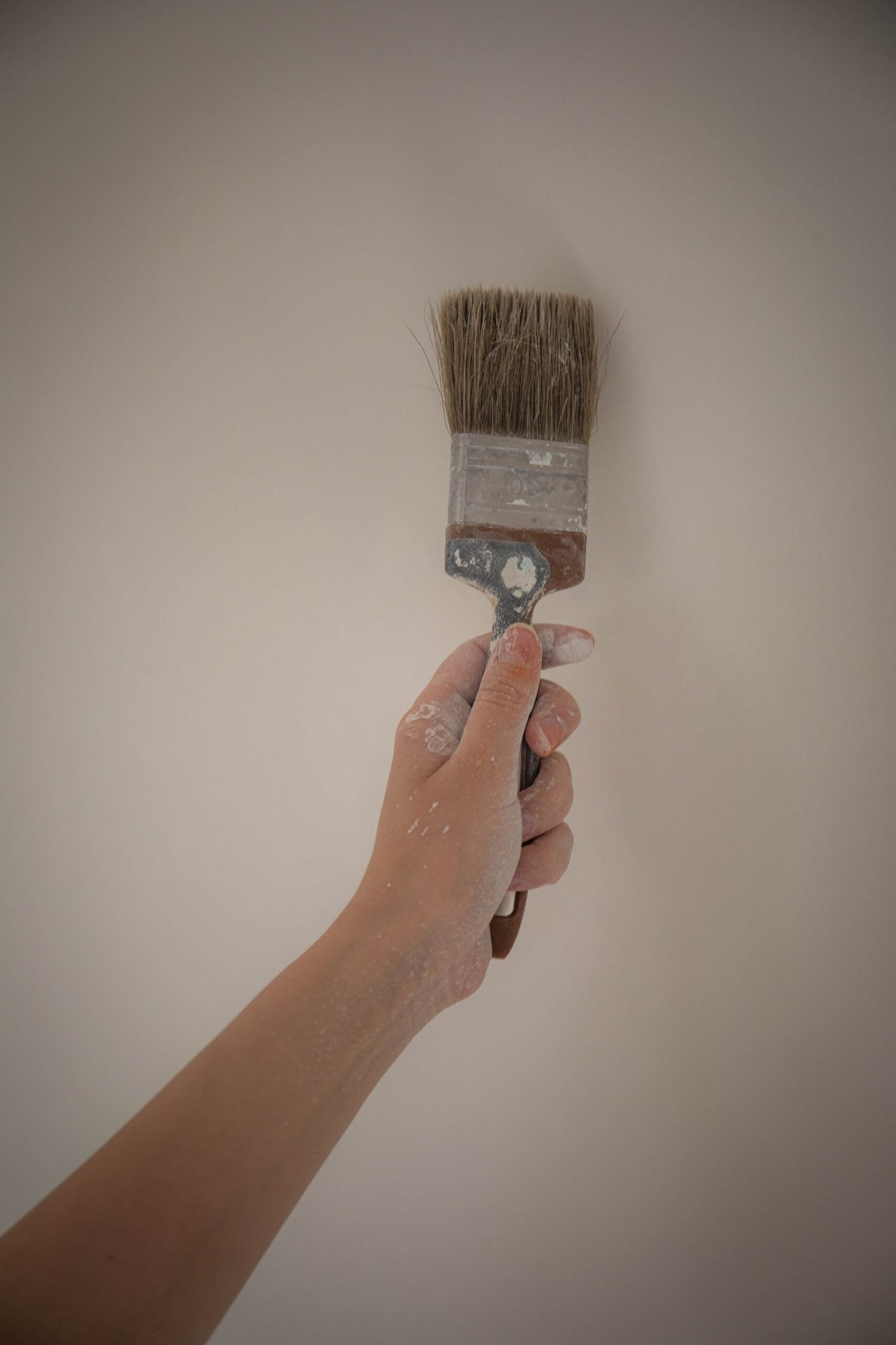 Hand applying white wall paint with a brush - illustrative stock photo