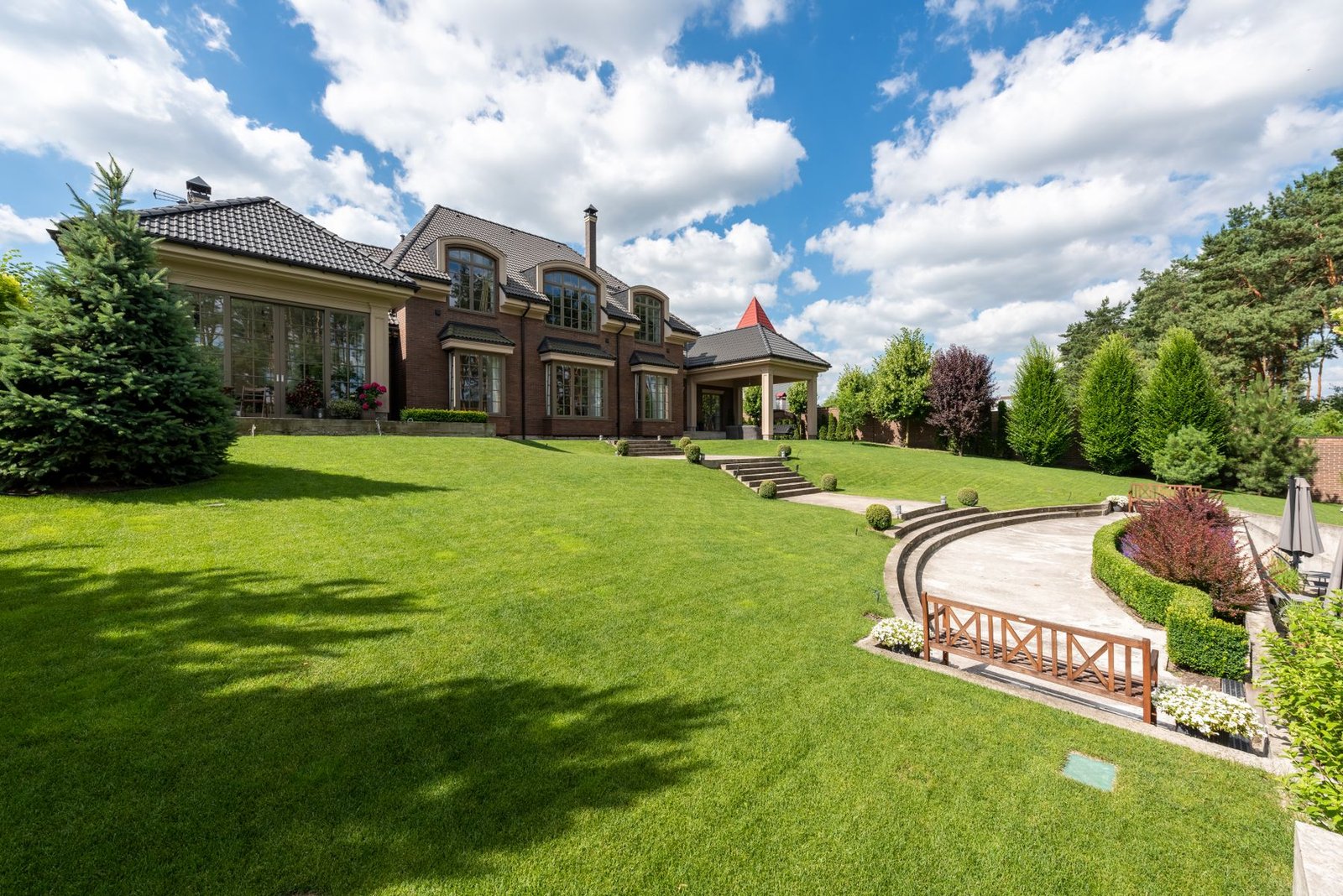 Large luxury mansion with a landscaped lawn and entrance steps - illustrative stock photo