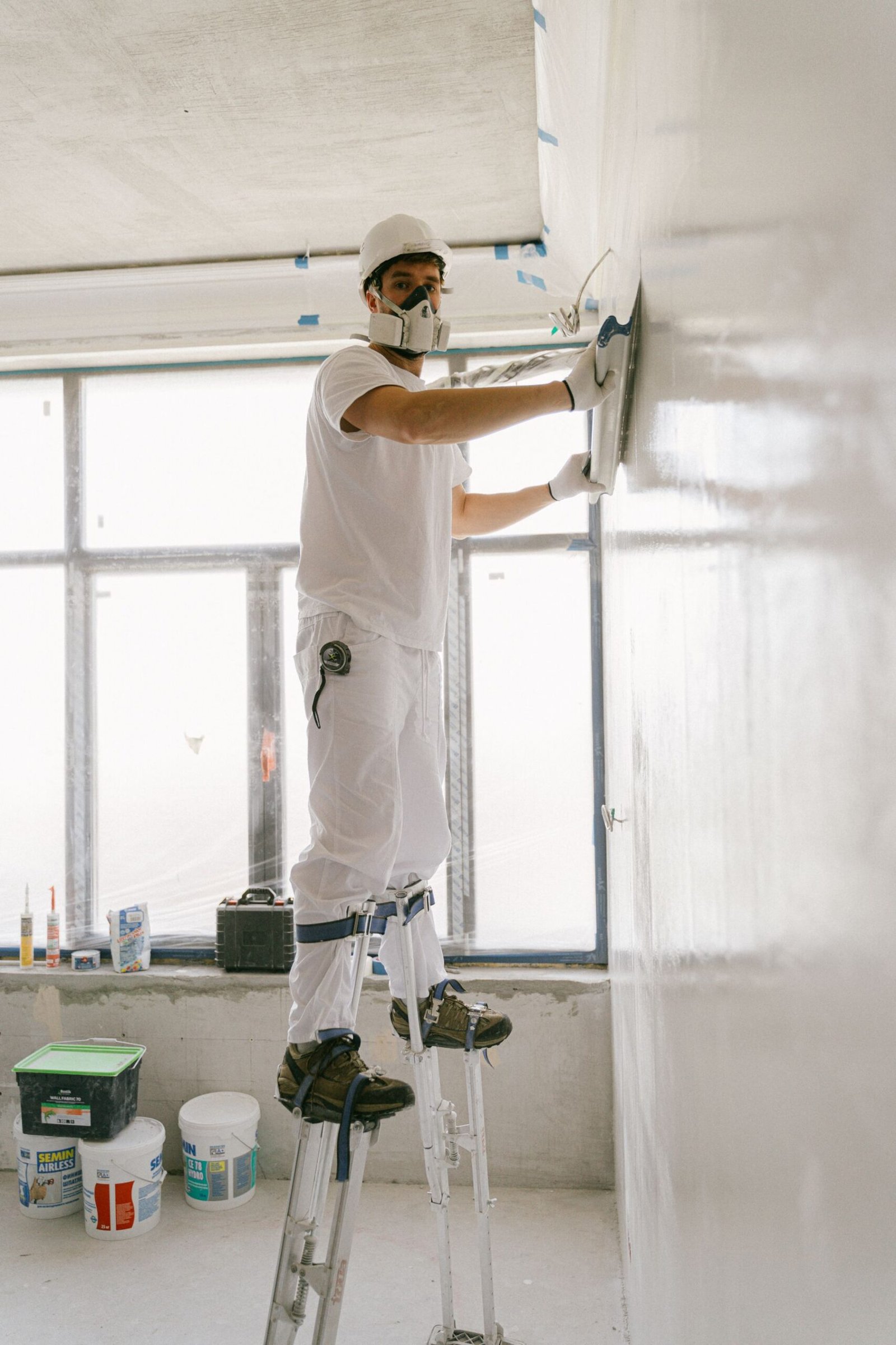 Worker smoothing a wall before painting - illustrative stock photo