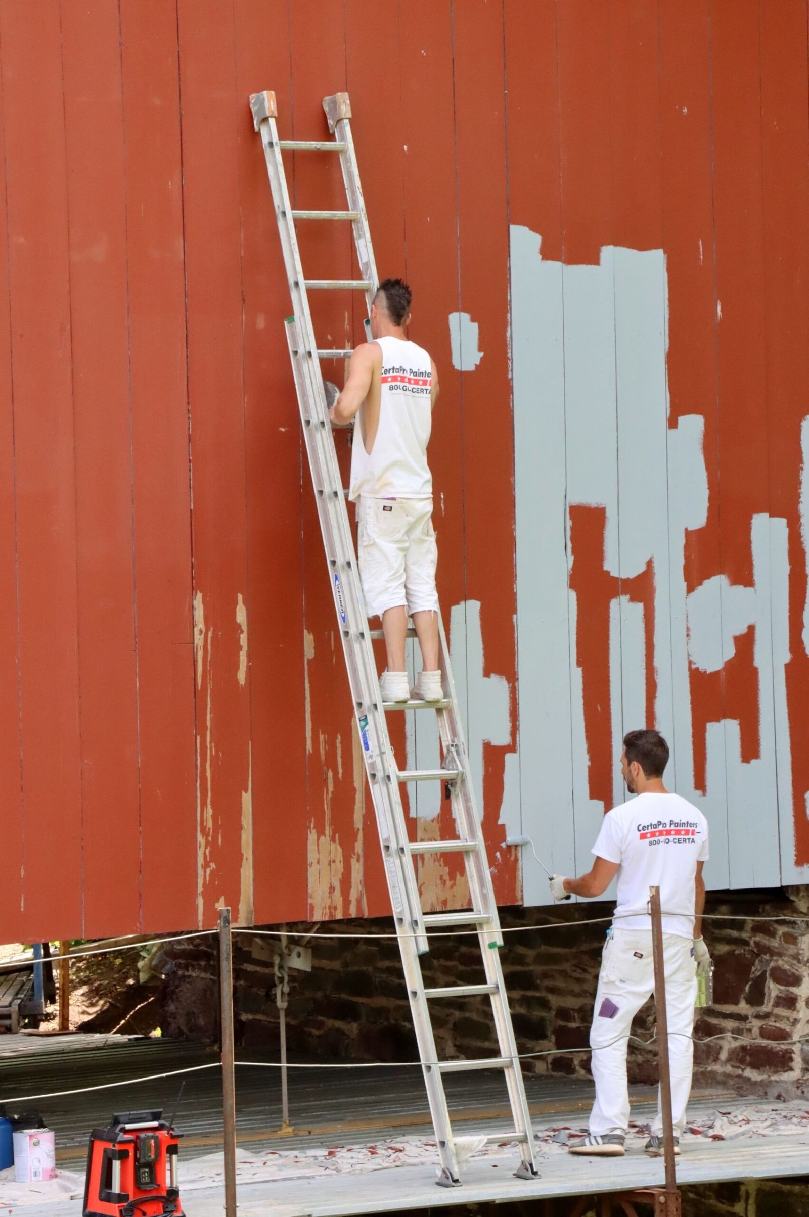Two painters in white workwear painting an exterior wall - illustrative stock photo