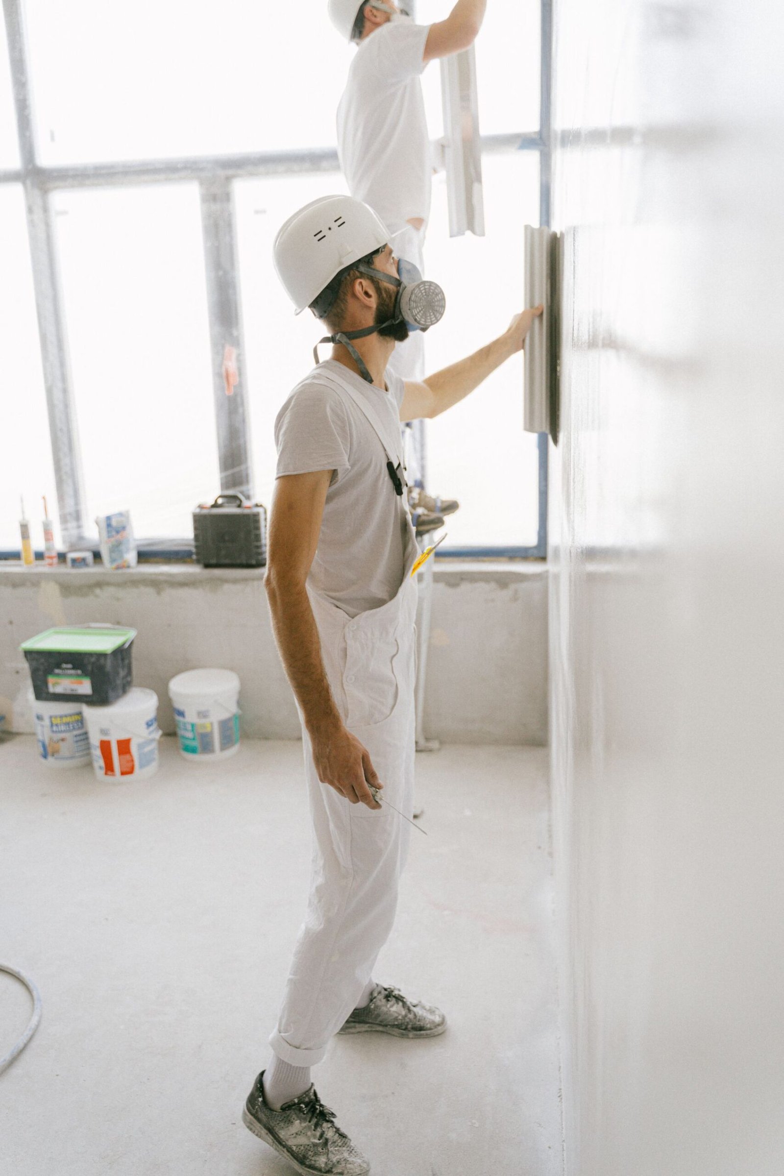 Workers in protective workwear finishing a wall - illustrative stock photo