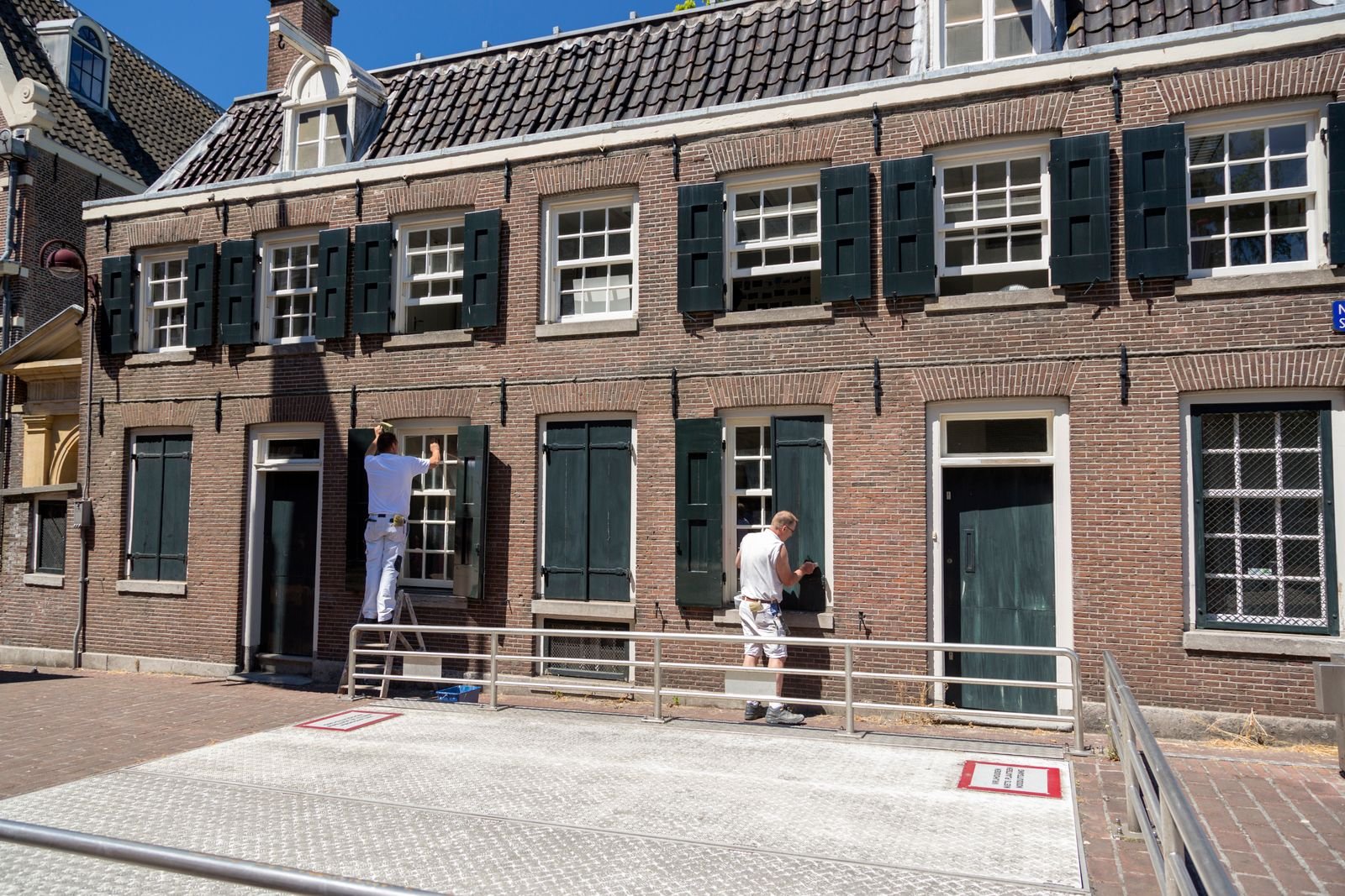 Two painters working on the exterior of a substantial brick house - illustrative stock photo