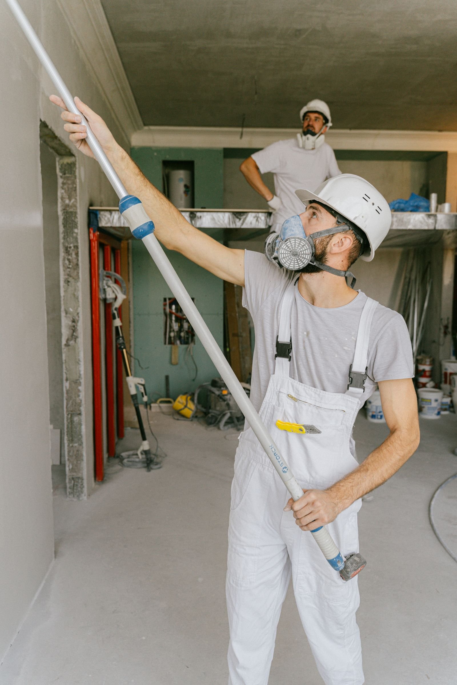 Two uniformed painters working together on interior walls - illustrative stock photo