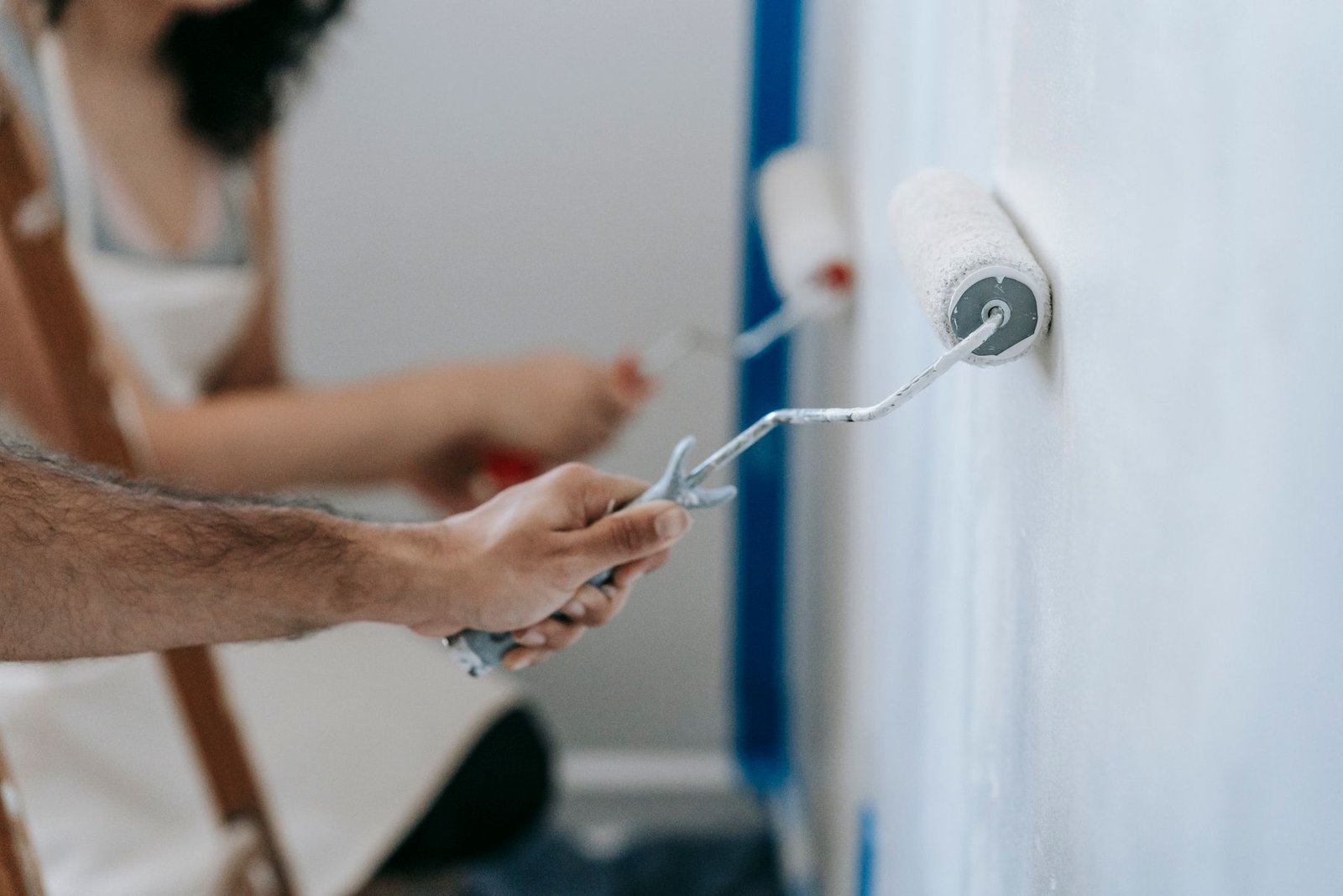 Two people painting a wall together with rollers - illustrative stock photo
