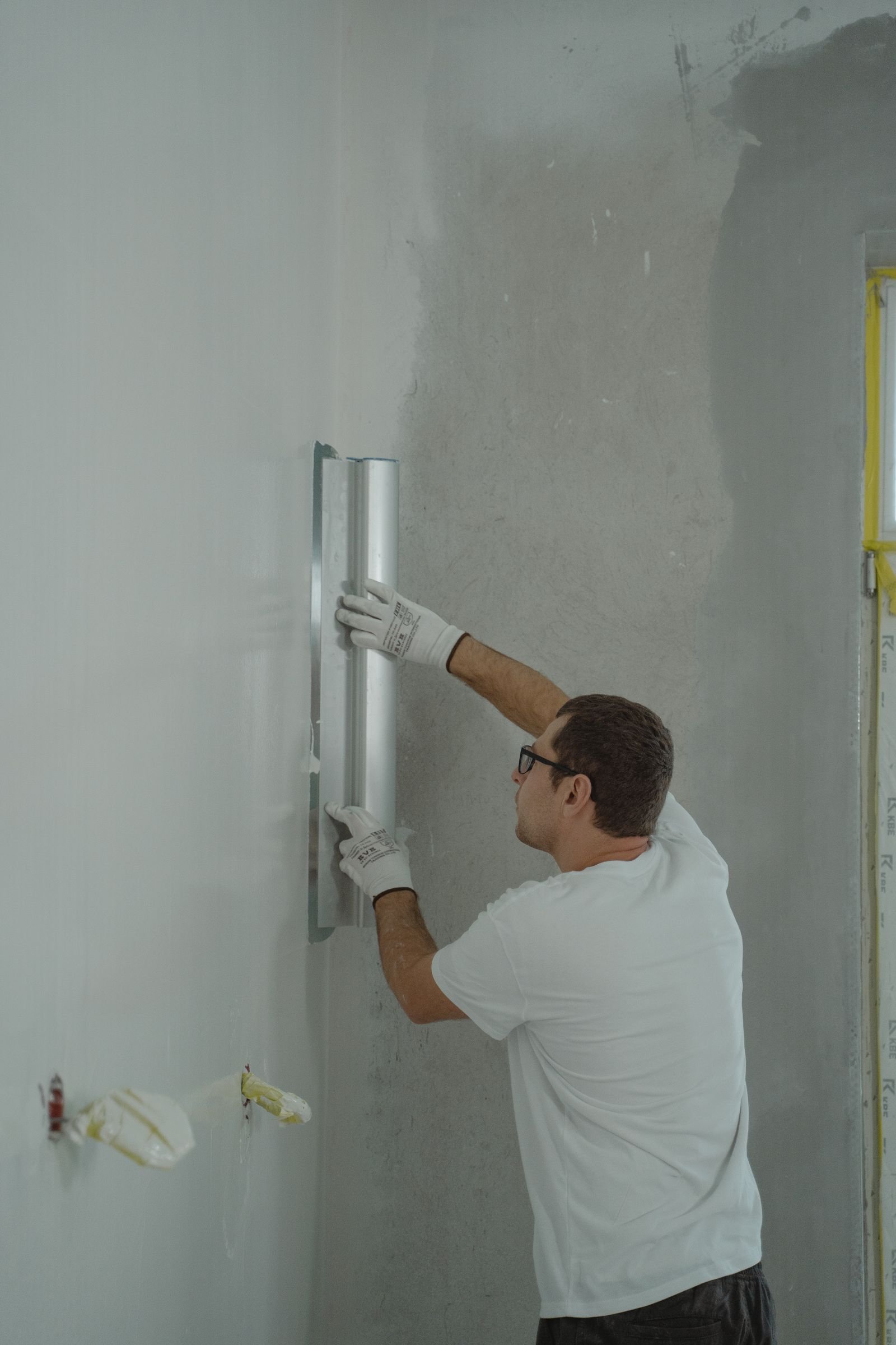 Worker renovating and smoothing an interior wall - illustrative stock photo