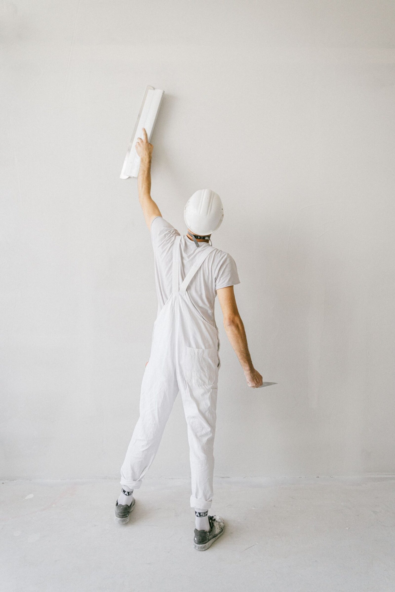 Painter in white overalls applying a fresh wall finish - illustrative stock photo
