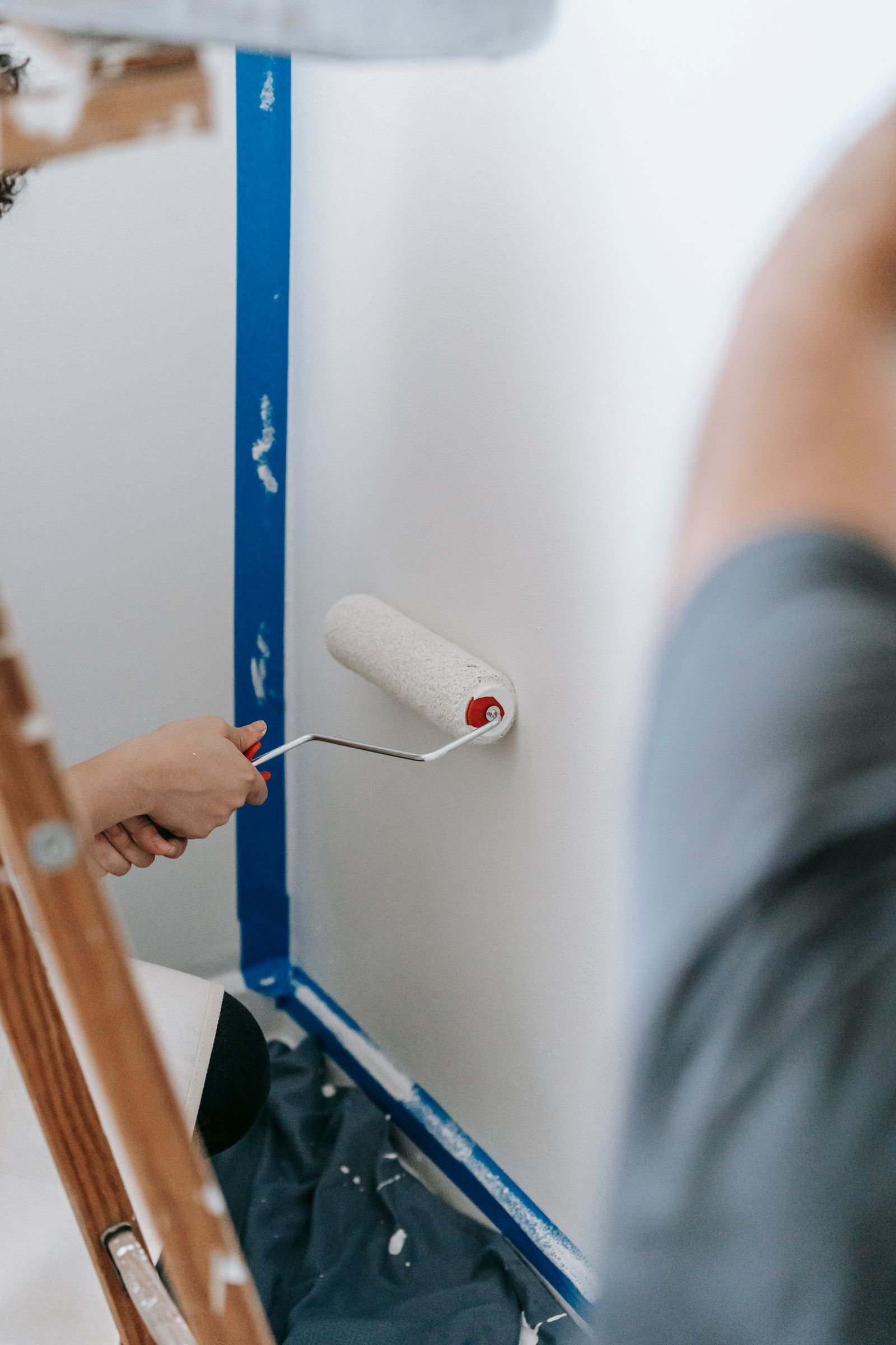 People applying fresh paint to an interior wall - illustrative stock photo