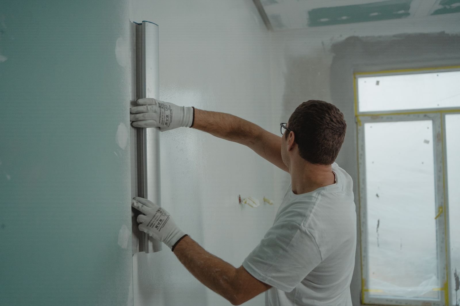 Worker checking and finishing an interior wall during remodeling - illustrative stock photo