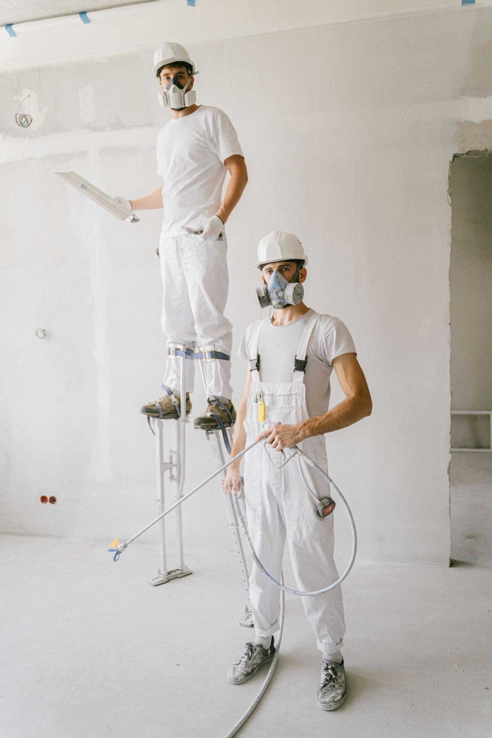 Two workers in white workwear preparing interior walls - illustrative stock photo