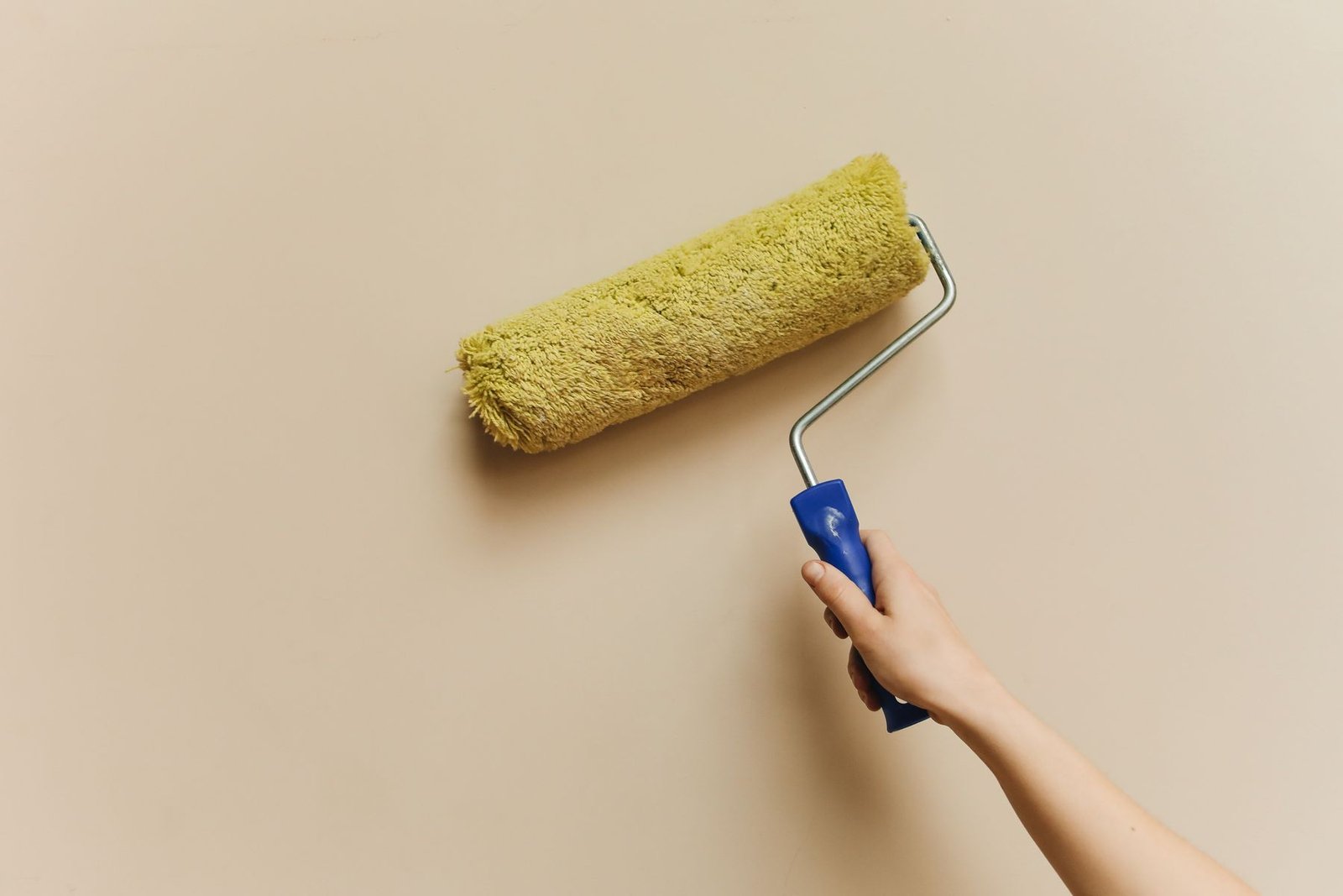 Hand applying wall paint with a roller - illustrative stock photo