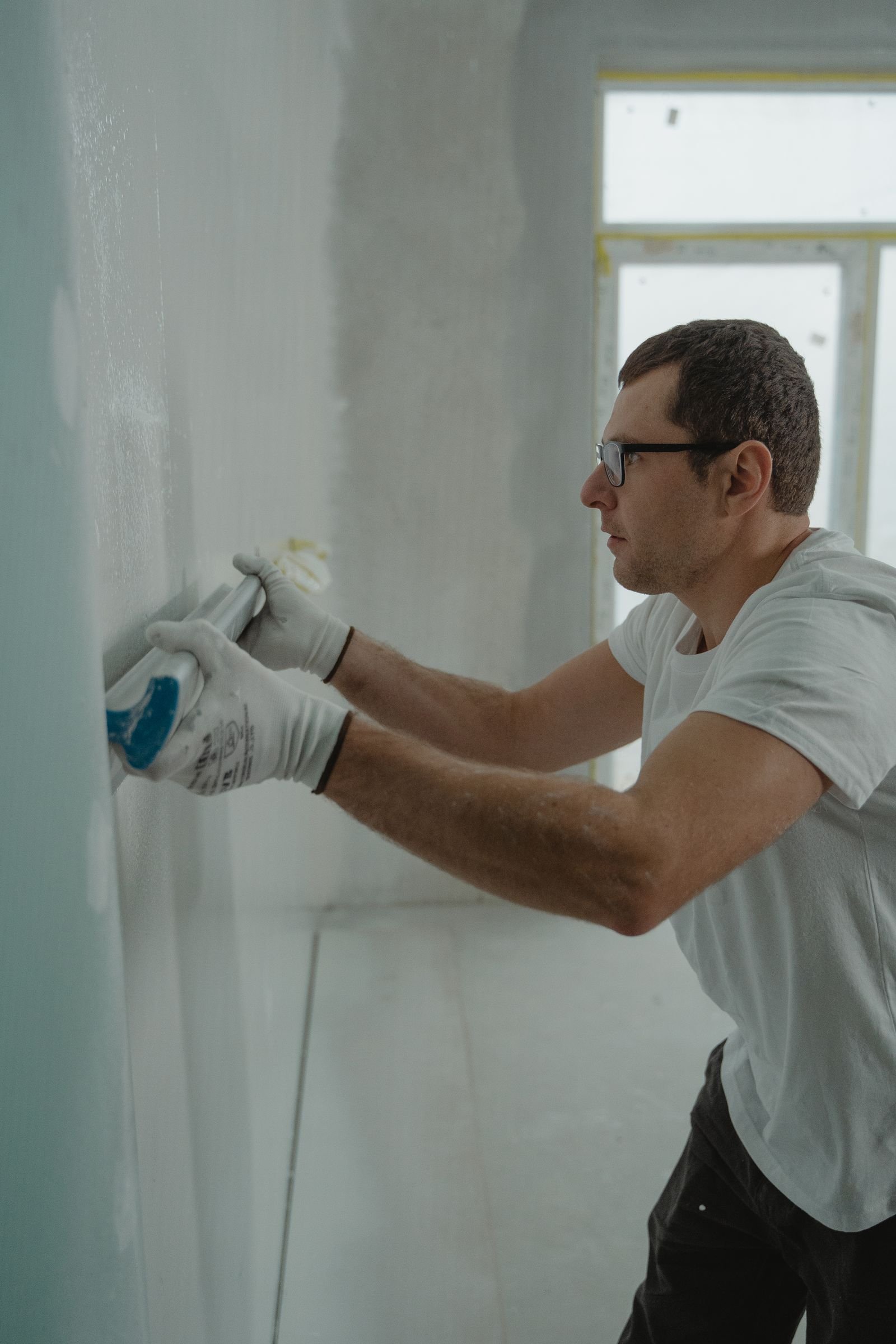 Worker applying compound to an interior wall - illustrative stock photo