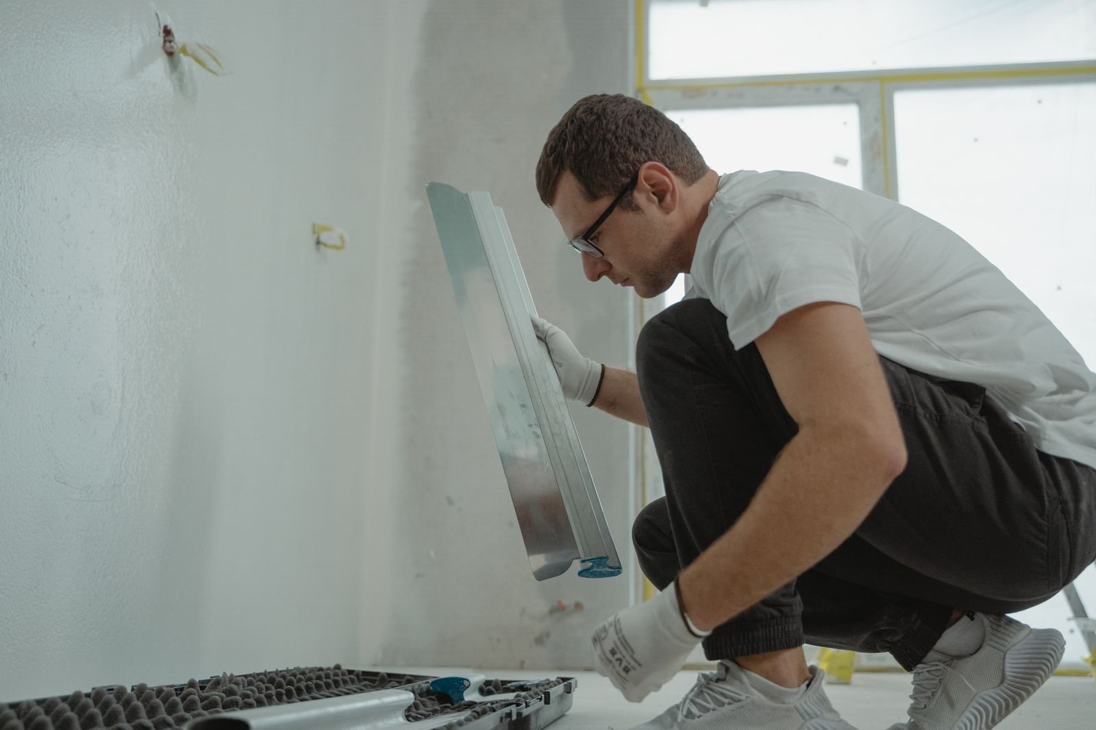 Worker preparing a wall with a metal trowel - illustrative stock photo