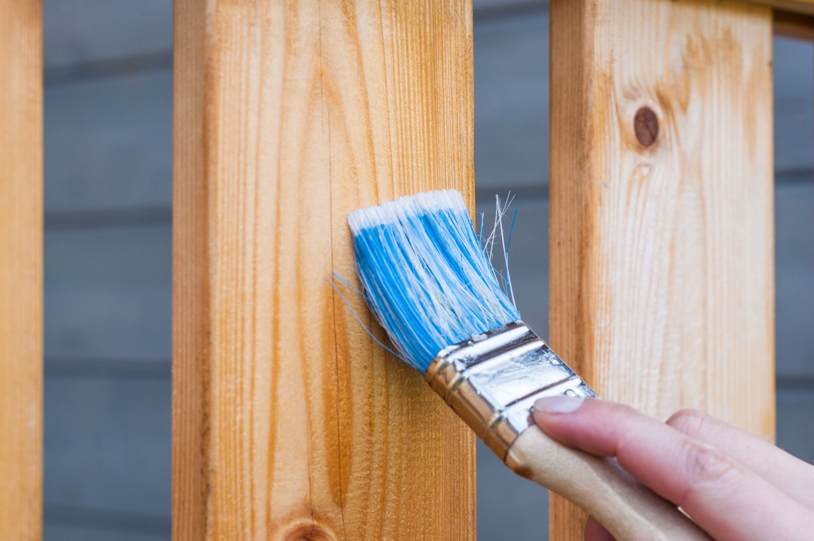 Hand brushing paint onto an exterior wooden surface - illustrative stock photo