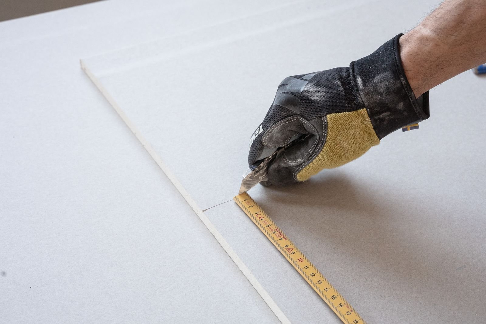 Gloved worker taking precise measurements during a renovation - illustrative stock photo