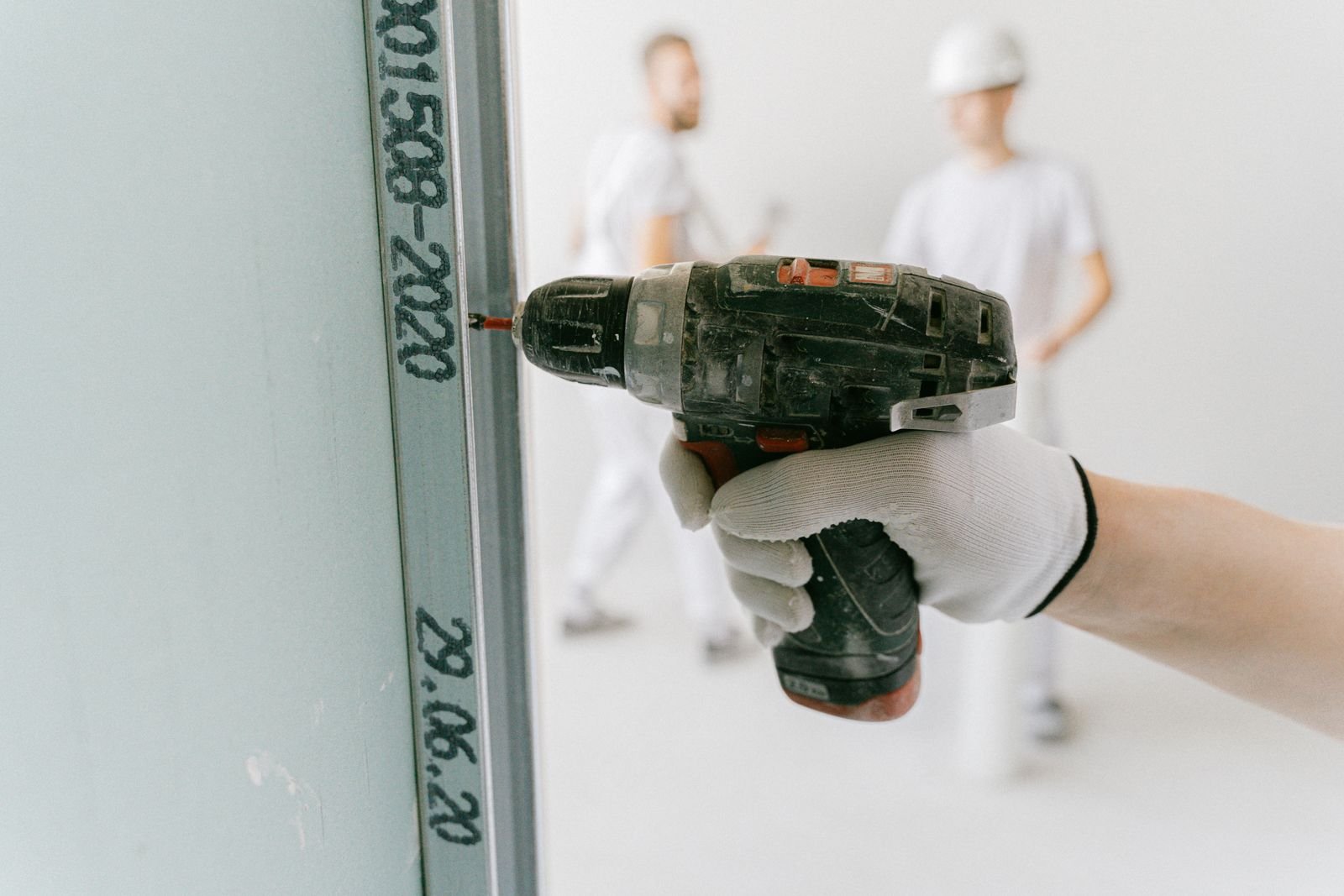 Worker using a drill on drywall during an interior renovation - illustrative stock photo