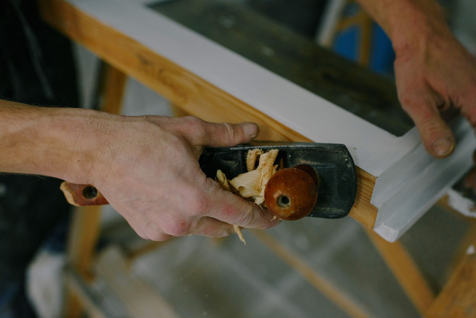 Craftsperson preparing a wooden frame with a hand plane - illustrative stock photo