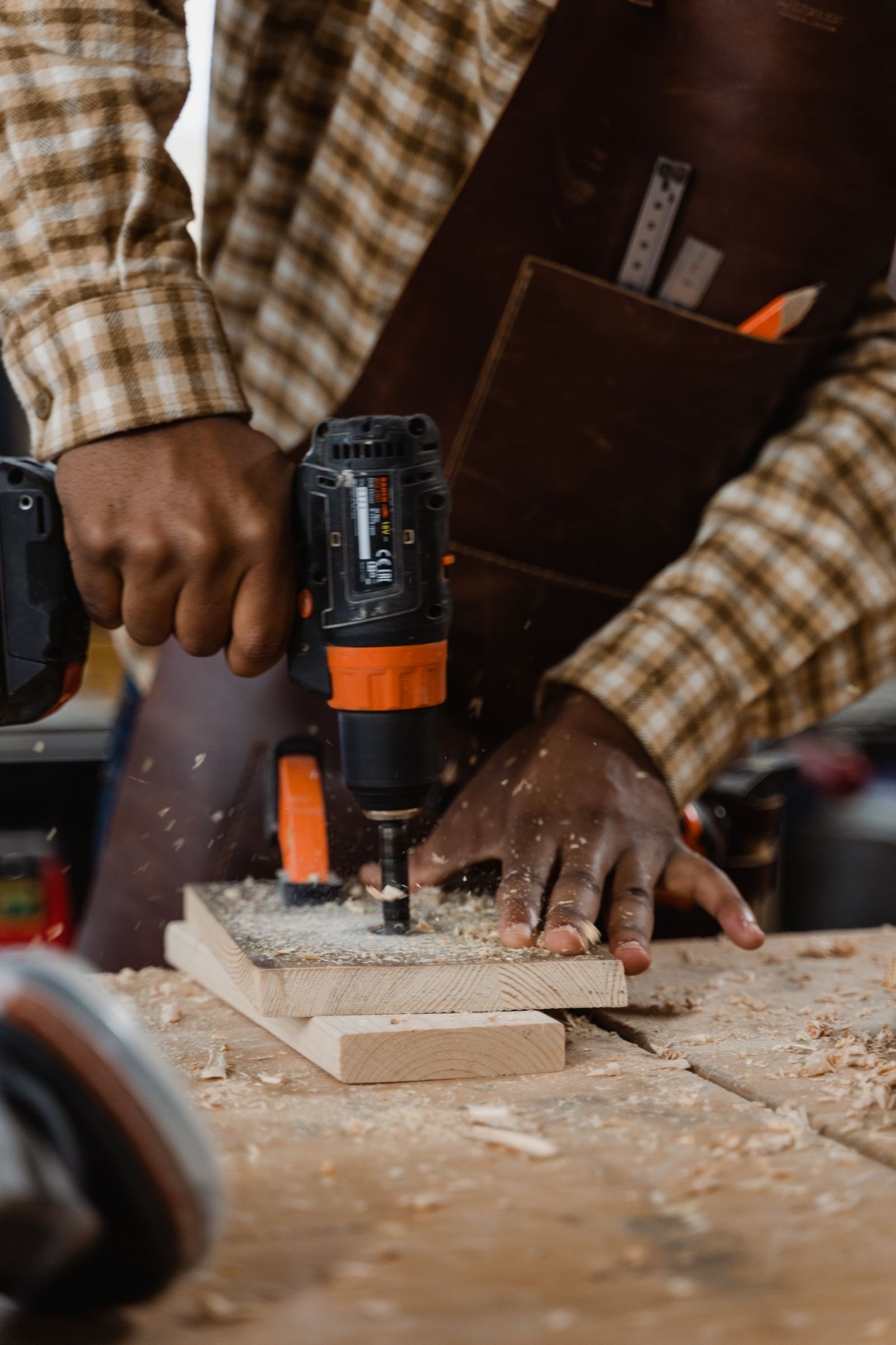 Close-up of a craftsperson drilling wood - illustrative stock photo