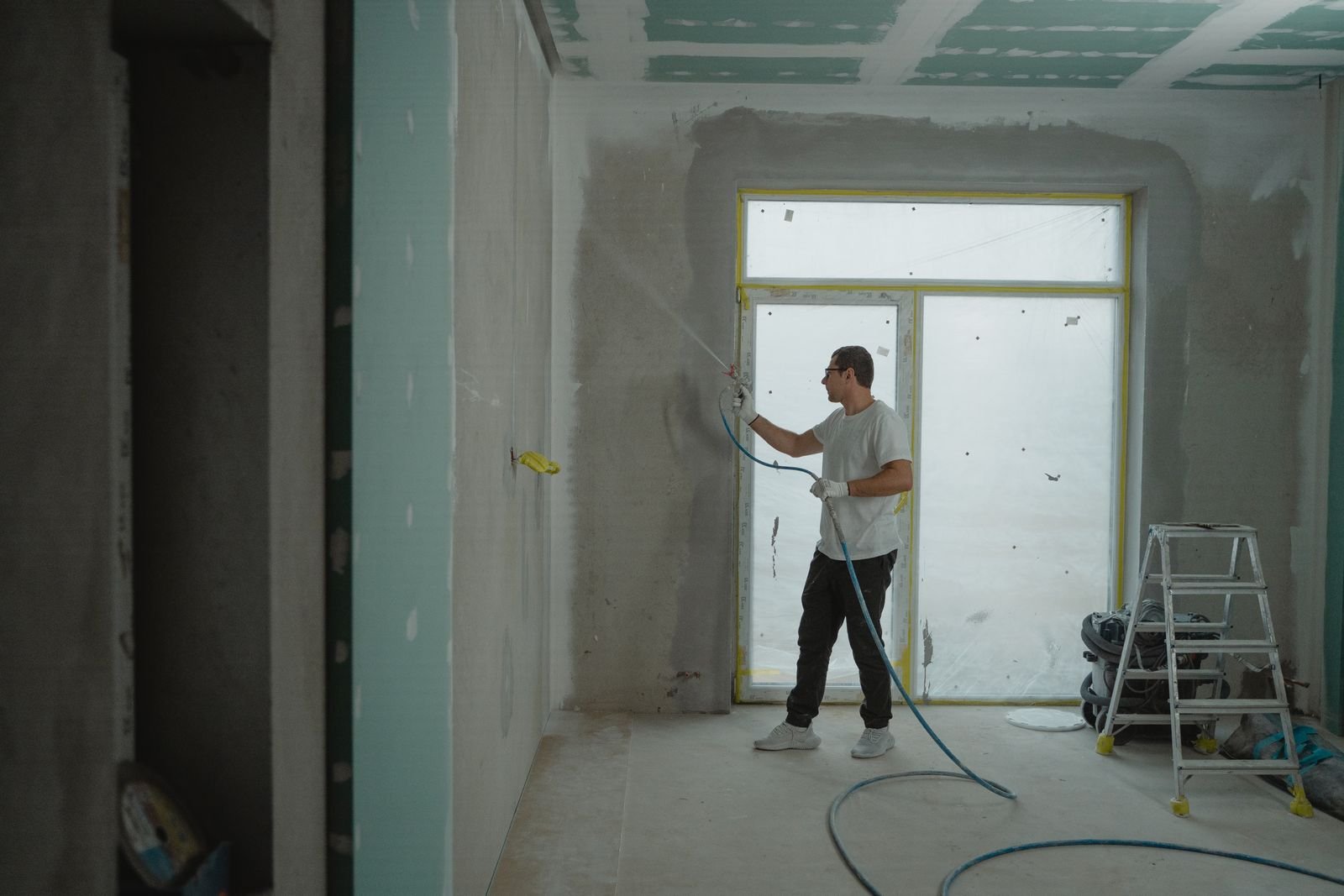 Worker spray finishing an interior wall - illustrative stock photo