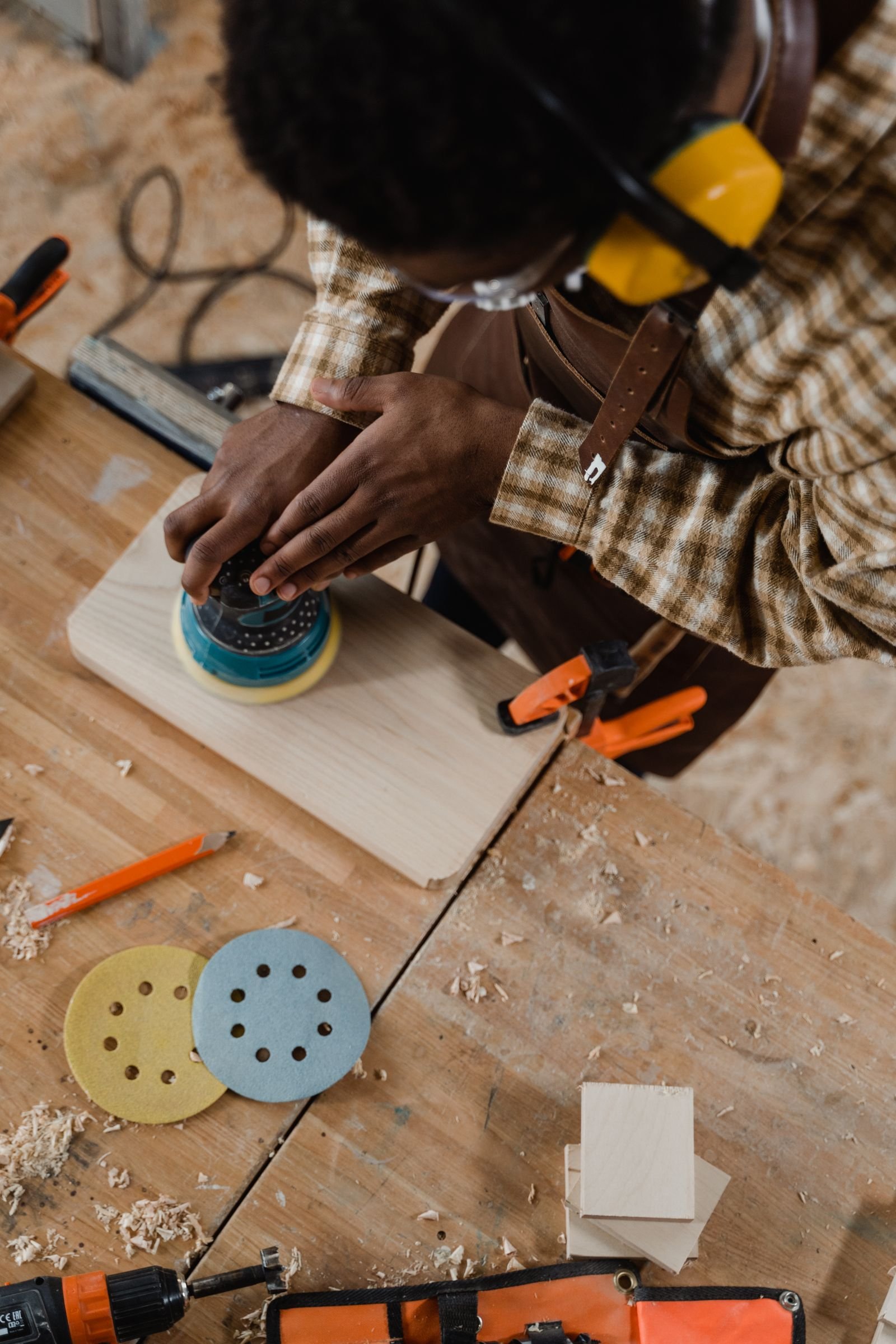 Craftsperson sanding wood with an orbital sander - illustrative stock photo