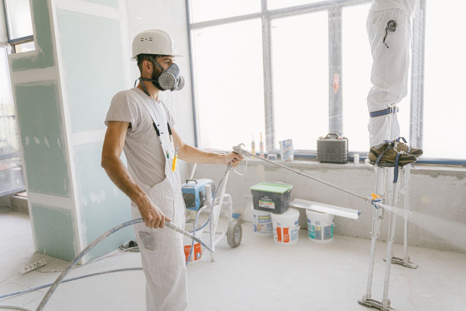 Two painters in protective workwear preparing interior surfaces - illustrative stock photo
