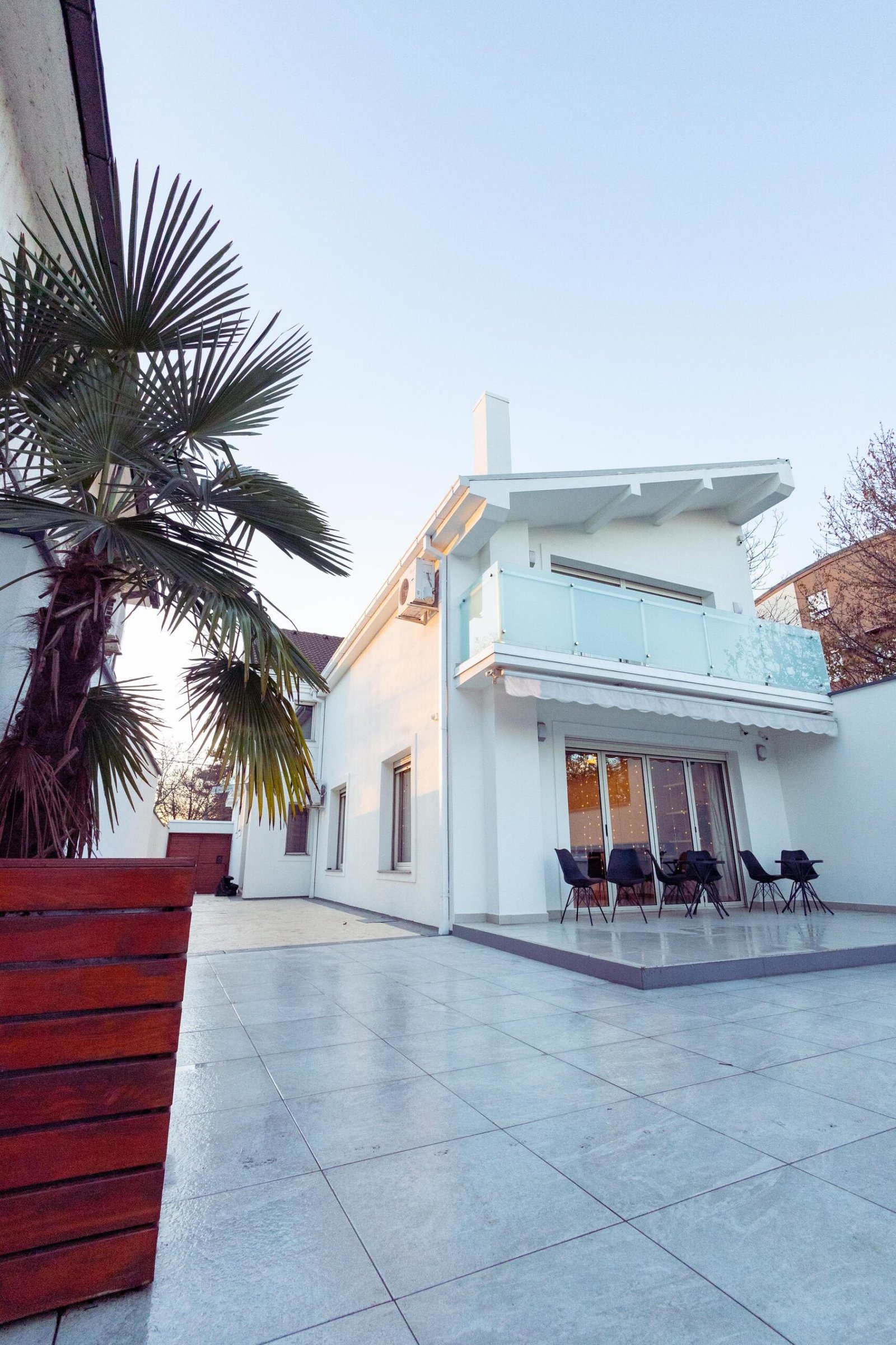 Large modern white house with palm trees and an outdoor patio - illustrative stock photo